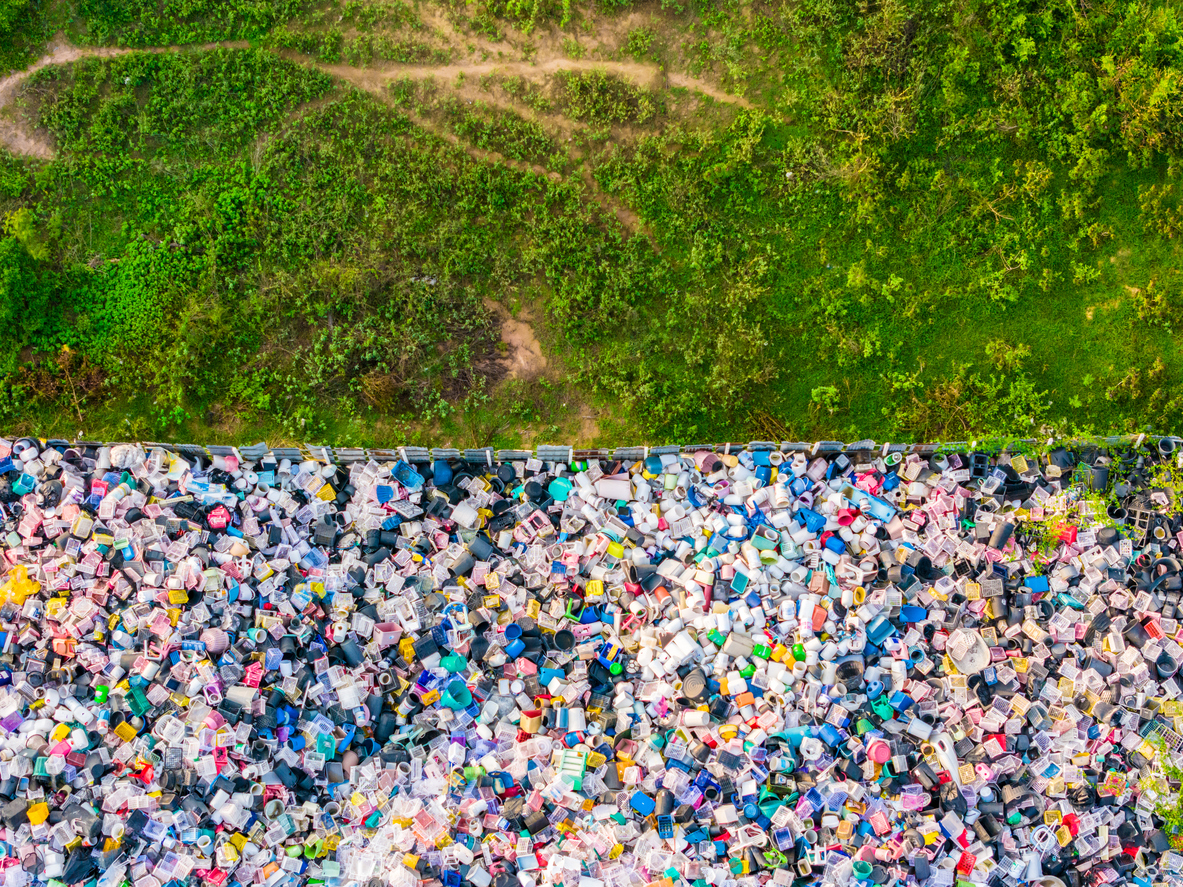 Aerial top view of concept contrast between clean green meadow and plastic landfill.