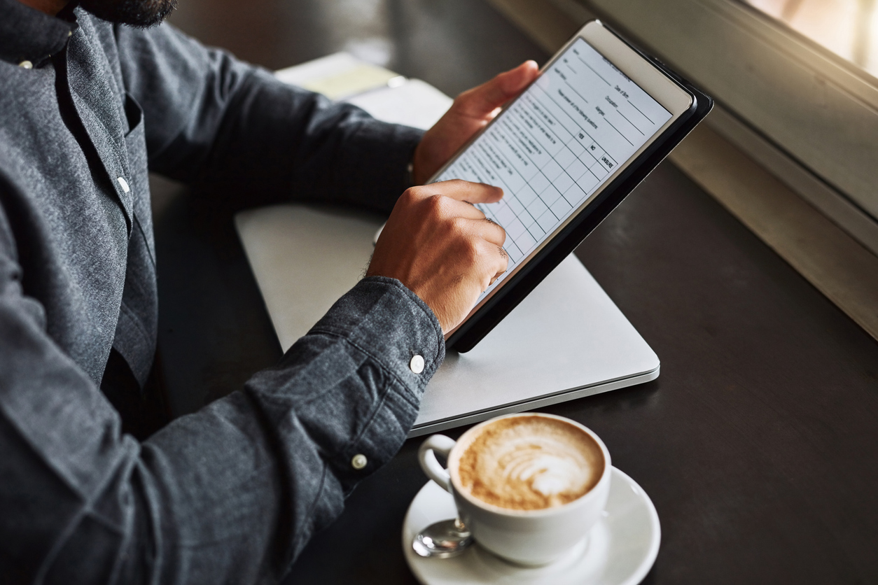 Cropped shot of an unrecognizable man using a digital tablet while sitting in a coffeeshop