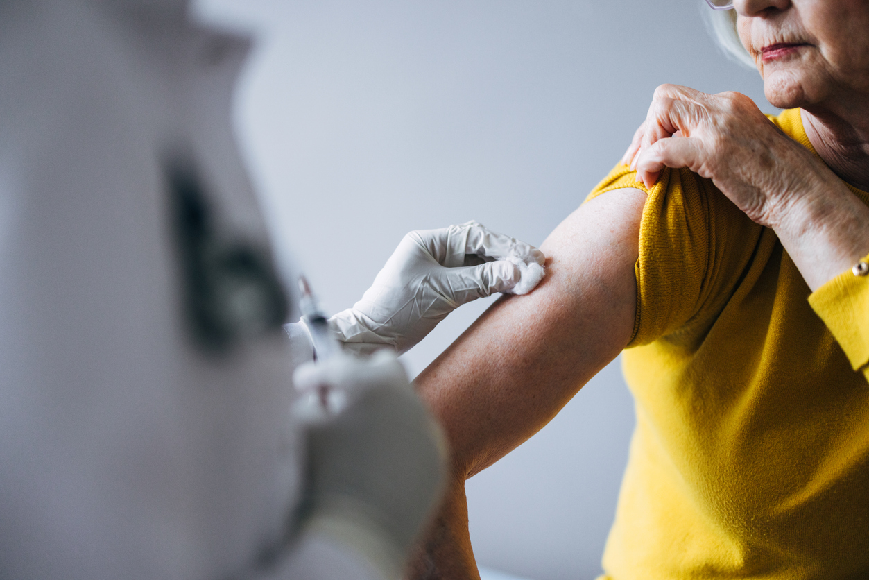 Healthcare professional administering a vaccination to an elderly woman
